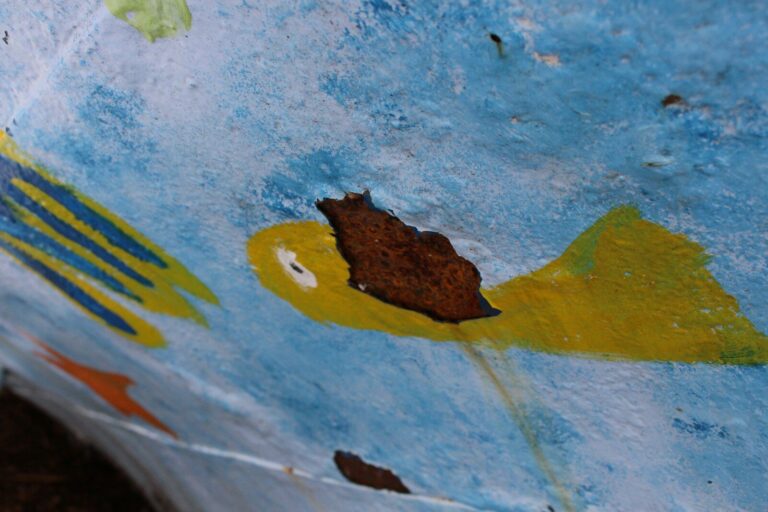 A close-up of a rusty, painted surface with fish designs.